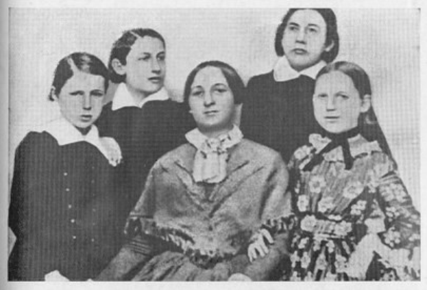 Schwarzes und weißes Foto einer vielseitigen Gruppe von Frauen, mit einer sitzenden Frau in der Mitte und dem Text "Die Frauenwahlrechtsbewegung" unten.