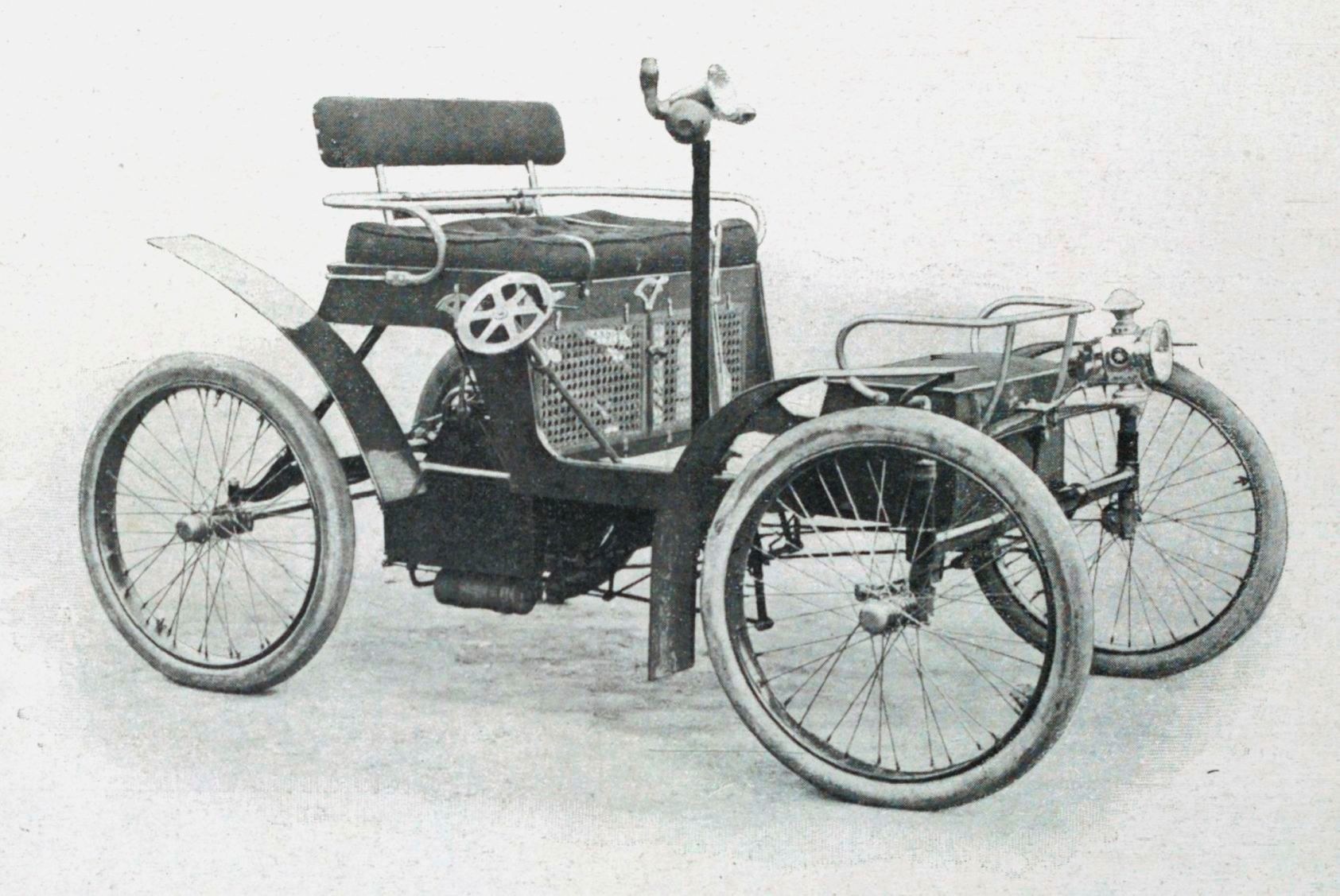 Schwarzes und weißes Foto eines Elektroautos aus den frühen 1900er Jahren mit schlankem, aerodynamischem Design, großem runden Scheinwerfer, geschwungener Dachlinie, vier großen Rädern und einem prominenten Heckmotor.