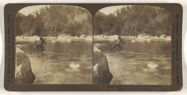 Altes Schwarz-Weiß-Foto eines Mannes, der in einen Fluss springt und von Felsen und Bäumen umgeben ist.