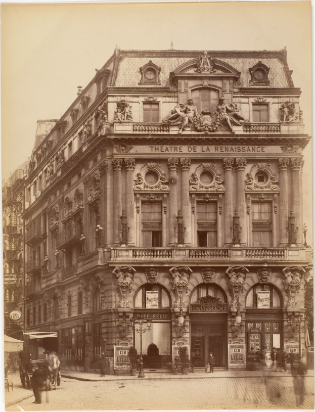 Altes Foto des Théâtre de la Renaissance in Paris mit seiner prunkvollen Fassade mit Fenstern, Säulen, Bögen und Skulpturen, mit ein paar Menschen und Fahrzeugen im Vordergrund und dem Himmel im Hintergrund.