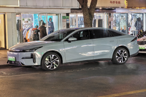 Ein Mitsubishi Lancer EV auf einer nächtlichen Stadtstraße geparkt, umgeben von Gebäuden, Schaufenstern, Schaufensterpuppen und beleuchteten Schildern.