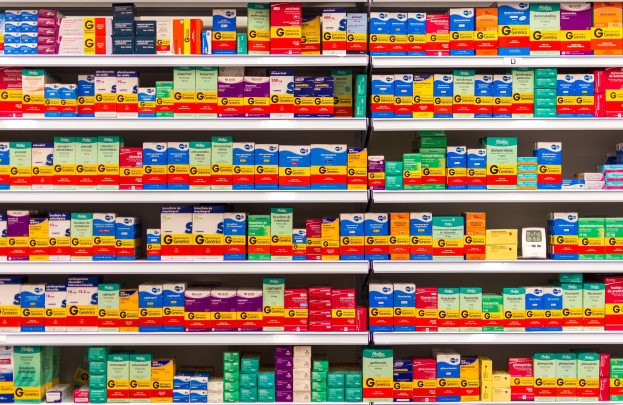 Ein Apothekenregal mit verschiedenen Medikamentenarten, darunter Schachteln und andere Gegenstände, die ordentlich auf den Regalen angeordnet sind.
