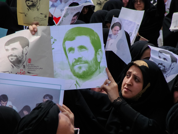 Eine Gruppe iranischer Frauen in schwarzer Kleidung, einige mit Brille, halten Bilder von Präsident Mahmoud Ahmadinejad während einer Kundgebung in Tehran hoch.