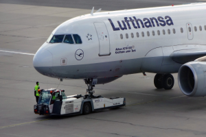 Lufthansa Airbus A319-100 auf der Startbahn des Frankfurter Flughafens mit einem Bodenfahrzeug und einer Person in der Nähe, bereit zum Start.