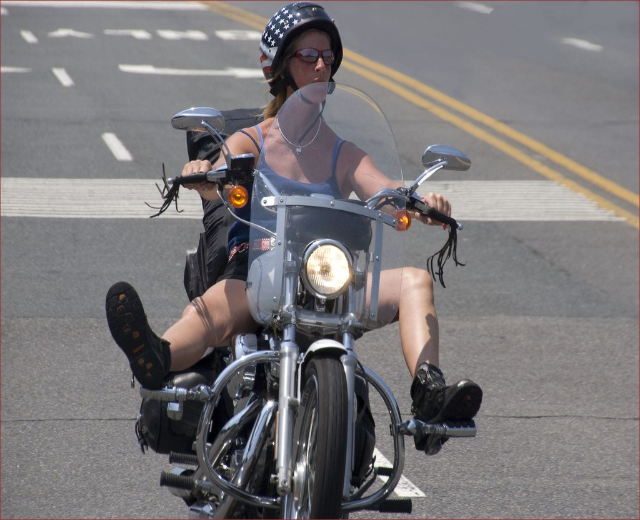 Eine Frau fährt ein Fahrrad auf einer Straße und trägt einen schwarzen Helm.