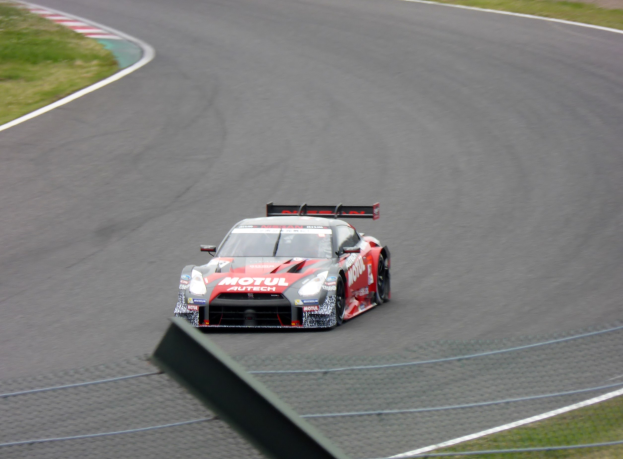 Ein Nissan GT-R Nismo GT3 Rennauto auf der Nürburgring 24 Stunden Strecke, mit grünem Gras auf beiden Seiten der Straße.