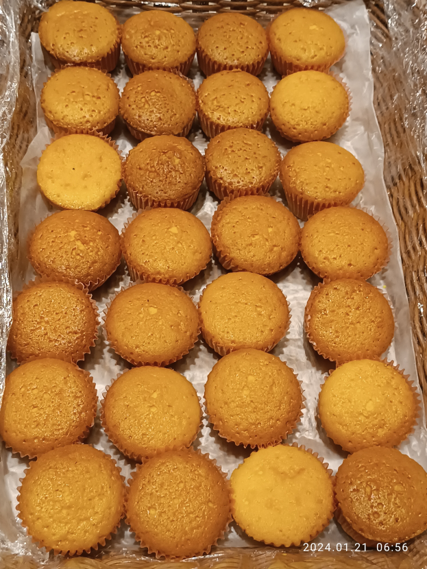 Ein Korb voller ordentlich arrangierter Cupcakes auf einem Tisch, mit einem Wasserzeichen auf dem Bild.