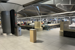 Großer Raum mit mehreren Tischen, Stühlen, Mülltonnen, Maschinen, Säulen und Deckenleuchten, Teil des neuen Terminals am Frankfurt Airport.