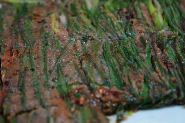 Nahaufnahme eines Steaks mit goldbrauner Kruste und saftigem Inneren neben zarten Spargelstangen auf einem weißen Teller, garniert mit Kräutern und Gewürzen.