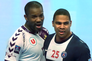 Zwei Männer in weißen und blauen T-Shirts auf einem Fußballfeld, die einen Sieg mit einem hellblauen Hintergrund feiern.
