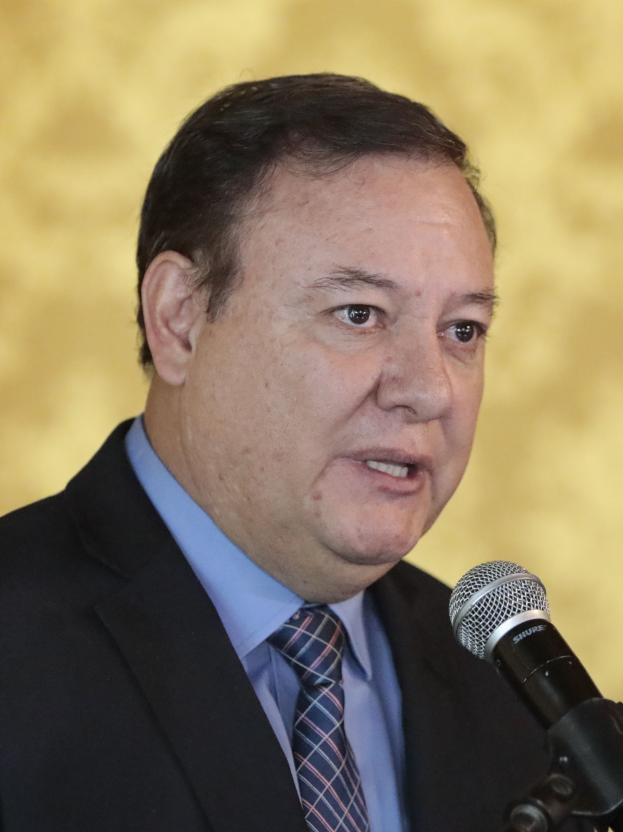 Ein Mann im Anzug und Krawatte spricht in ein Mikrofon und wird als Generalstaatsanwalt identifiziert.