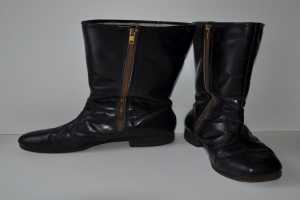 Schwarze Lederstiefel mit silbernen Reißverschlüssen auf einer weißen Oberfläche, mit einem glänzenden Finish.
