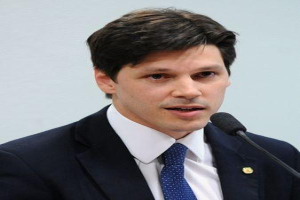 Ein Mann in Anzug und Krawatte spricht in ein Mikrofon an einem Podium, wahrscheinlich um die Genehmigung eines Gesetzes zur Verbots des Internetgebrauchs anzusprechen.